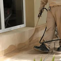 General pest control technician spraying exterior perimeter around a home in Tempe, AZ