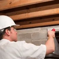 Termite inspection technician checking a basement wall and framing for termite activity in Tempe, AZ